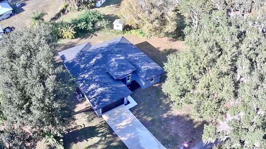 An aerial view shows a single-story house with a dark roof and a concrete driveway — 121 ARGYLE AVENUE, FROSTPROOF, FL