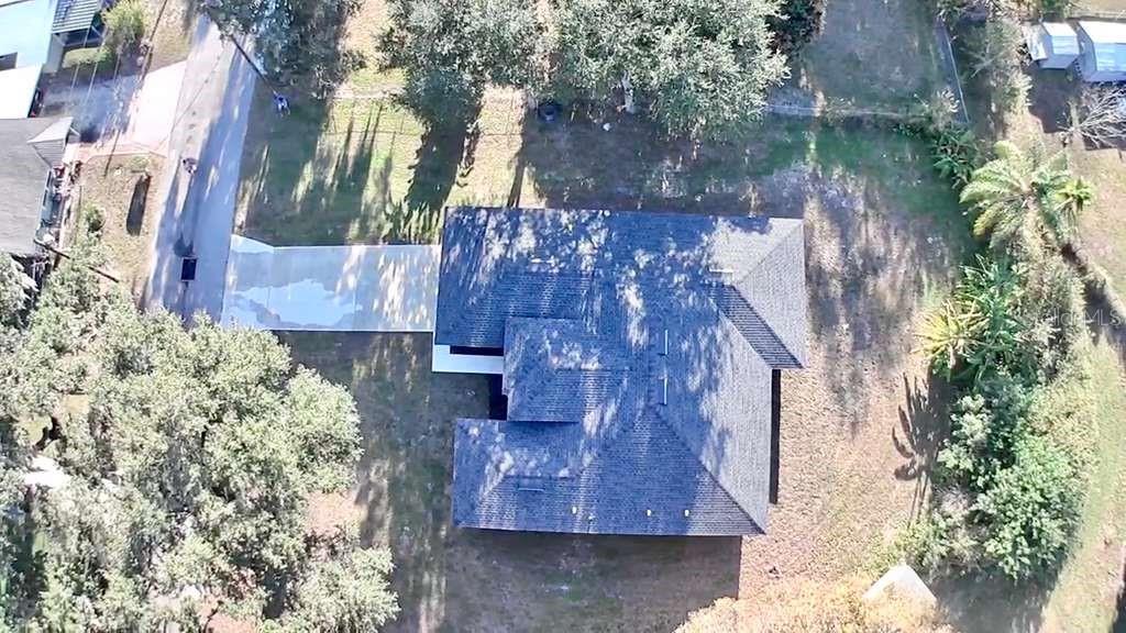An aerial view shows a house with a dark shingled roof and a concrete driveway — 121 ARGYLE AVENUE, FROSTPROOF, FL