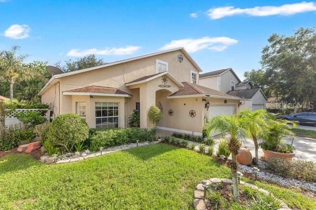 A two-story tan stucco house with a front lawn and a palm tree — 84 KNIGHTS HOLLOW DRIVE, APOPKA, FL