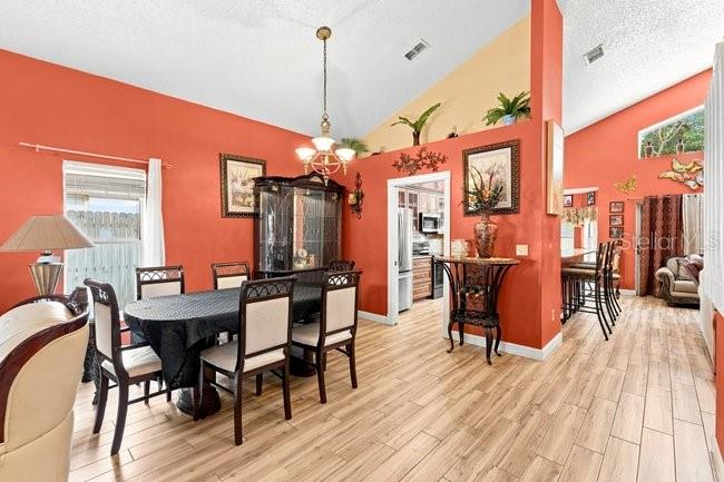A dining room features a dark table, six chairs, a china cabinet, and orange walls — 84 KNIGHTS HOLLOW DRIVE, APOPKA, FL