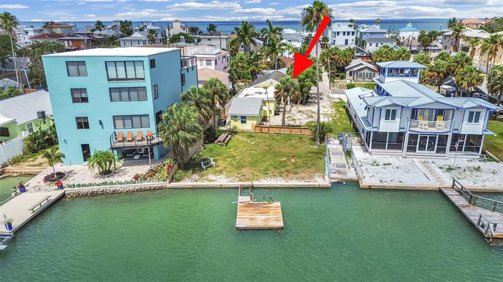 An aerial view shows a waterfront property with a small house between two larger buildings — 201 90TH AVENUE, TREASURE ISLAND, FL