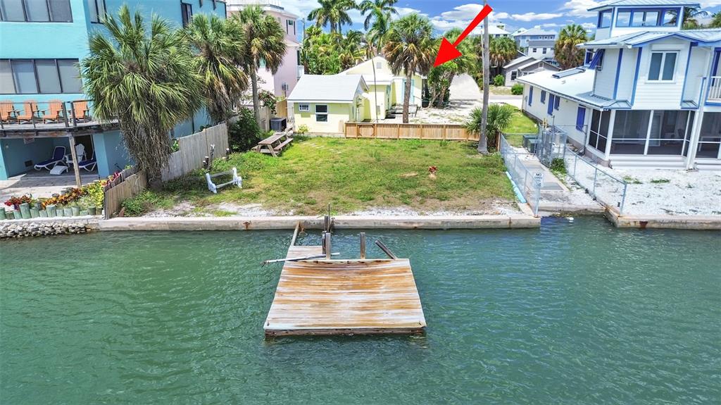 An aerial view of a waterfront property featuring a small house, docks, and surrounding homes — 201 90TH AVENUE, TREASURE ISLAND, FL