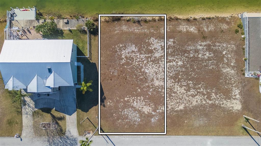 An aerial view shows a vacant rectangular waterfront lot situated between two residential properties — 3488 TRIGGERFISH DRIVE, HERNANDO BEACH, FL