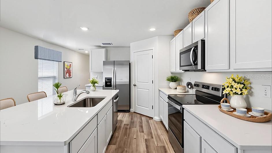 A modern kitchen features white cabinetry, a large island with a sink, and stainless appliances — 2094 NE 33RD LANE, OCALA, FL