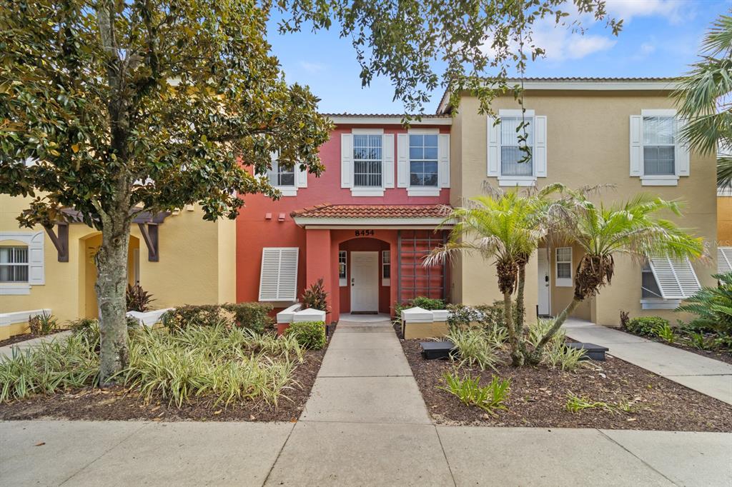 A two-story townhouse with a red facade, white shutters, and a central entryway — 8454 CRYSTAL COVE LOOP, KISSIMMEE, FL