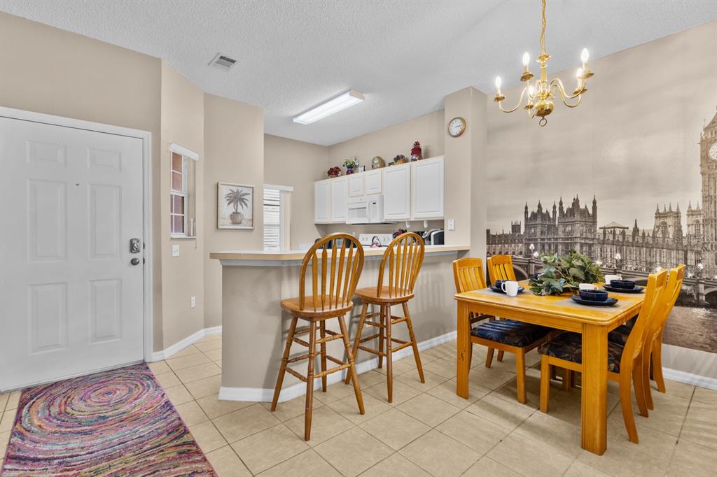 A dining area and kitchen breakfast bar with tile floors and a London mural wall — 8454 CRYSTAL COVE LOOP, KISSIMMEE, FL