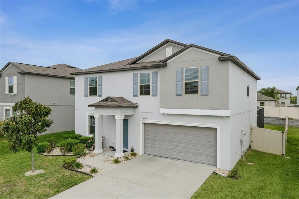 A two-story suburban house with a teal front door, gray garage, and light-colored stucco exterior — 4203 HANOVER DRIVE, NEW PORT RICHEY, FL