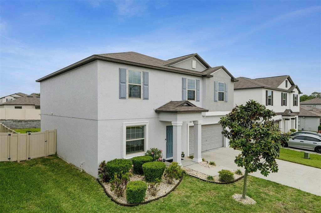 A two-story suburban house with a gray garage, light-colored stucco siding, and blue shutters — 4203 HANOVER DRIVE, NEW PORT RICHEY, FL