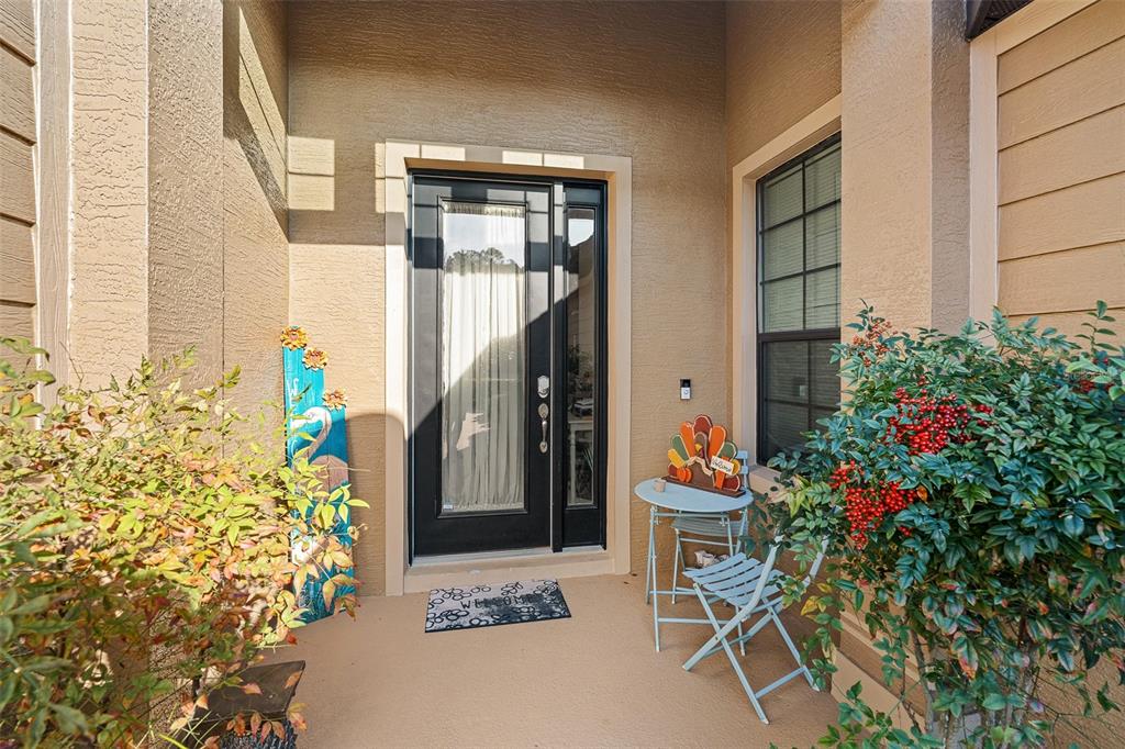A front entryway features a black door, a small bistro set, and decorative seasonal signage — 1047 KILKENNY LANE, ORMOND BEACH, FL