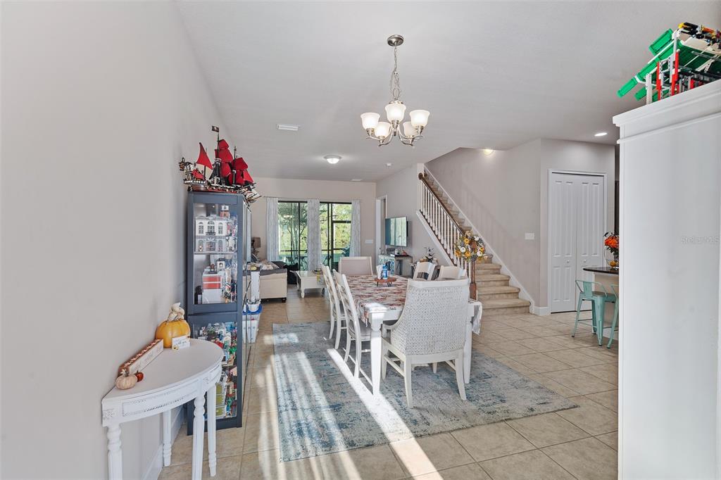 A dining area with a table, chairs, and a display cabinet sits near a staircase — 1047 KILKENNY LANE, ORMOND BEACH, FL