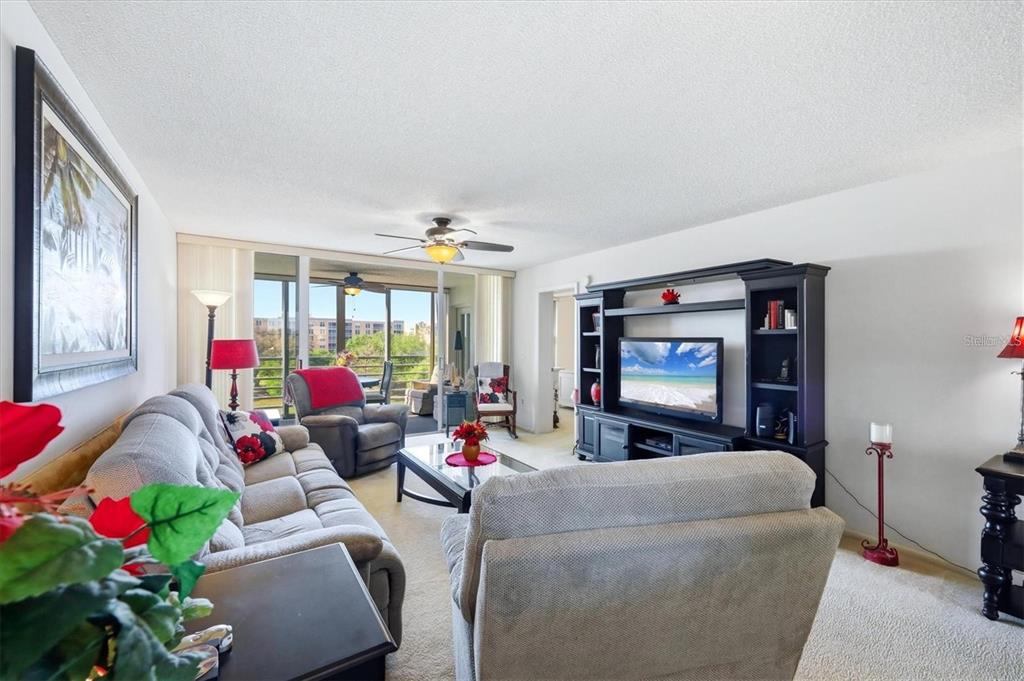 A living room features a grey sofa, a matching armchair, and a black entertainment center — 4460 FAIRWAYS BOULEVARD UNIT 302, BRADENTON, FL