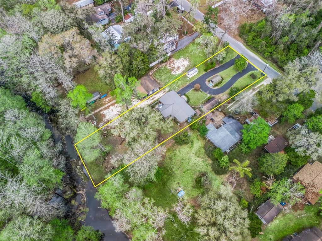 An aerial view shows a house with a driveway on a long, rectangular, tree-lined lot — 8701 CR 647 S, BUSHNELL, FL