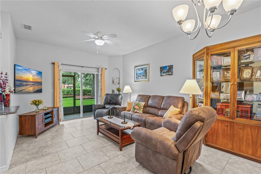 A living room features tile flooring, a brown sofa, two recliners, and a glass display cabinet — 104 MISTY GLEN LANE, DAYTONA BEACH, FL