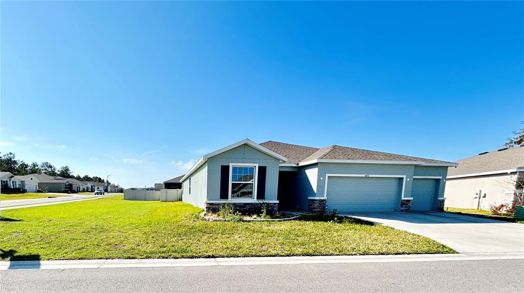 A single-story house with a light blue exterior, a two-car garage, and a front lawn — 6853 SE 3RD LOOP, OCALA, FL