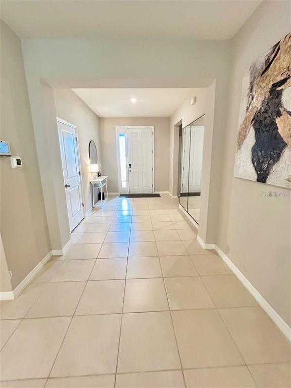 A tiled entryway leads to a white front door with a mirror and wall art — 6853 SE 3RD LOOP, OCALA, FL