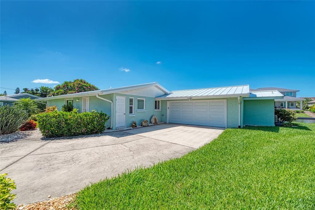 A light green single-story house with a white metal roof and a concrete driveway — 5577 CONTENTO DRIVE, SARASOTA, FL
