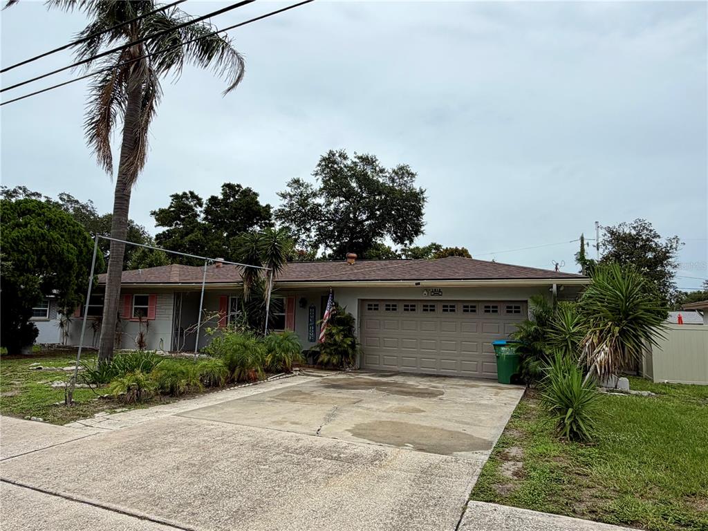 A single-story house with a concrete driveway, palm trees, and a gray exterior — 1513 S KEENE ROAD, CLEARWATER, FL