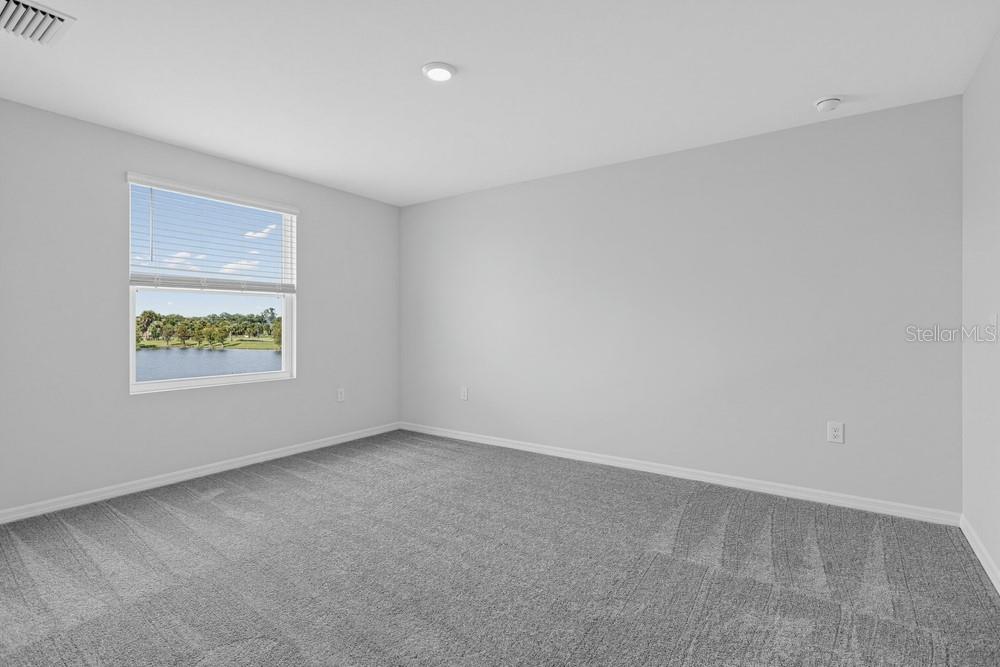 A room with beige carpet transitions into a tiled area featuring a staircase — 6753 EQUINOX LANE, NORTH FORT MYERS, FL