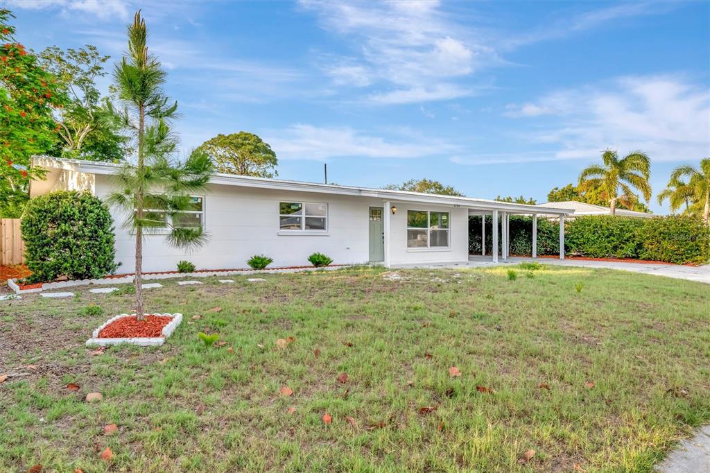 A white single-story house features a concrete driveway, a carport, and a gravel front yard — 2705 SUNNYSIDE STREET, SARASOTA, FL