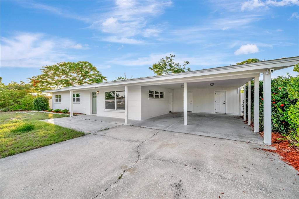 A single-story white house with a covered carport and a front yard with trees — 2705 SUNNYSIDE STREET, SARASOTA, FL