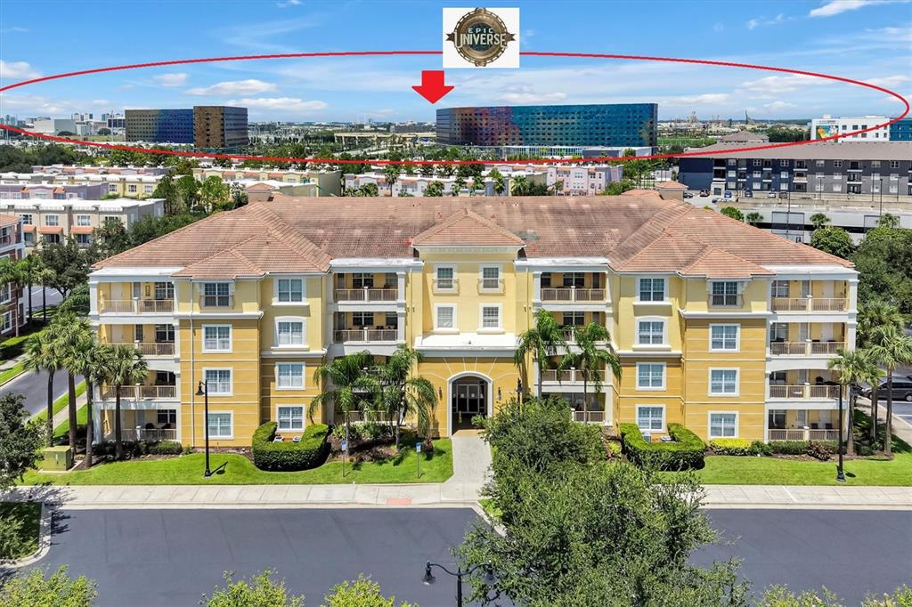 An exterior view of a multi-story yellow apartment building with a distant view of Epic Universe — 5025 SHOREWAY LOOP UNIT 30403, ORLANDO, FL