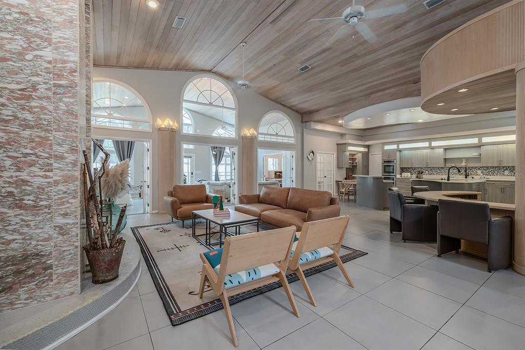 A spacious open-concept living room features a vaulted wood ceiling, tiled floors, and arched windows — 101 N ST ANDREWS DRIVE, ORMOND BEACH, FL