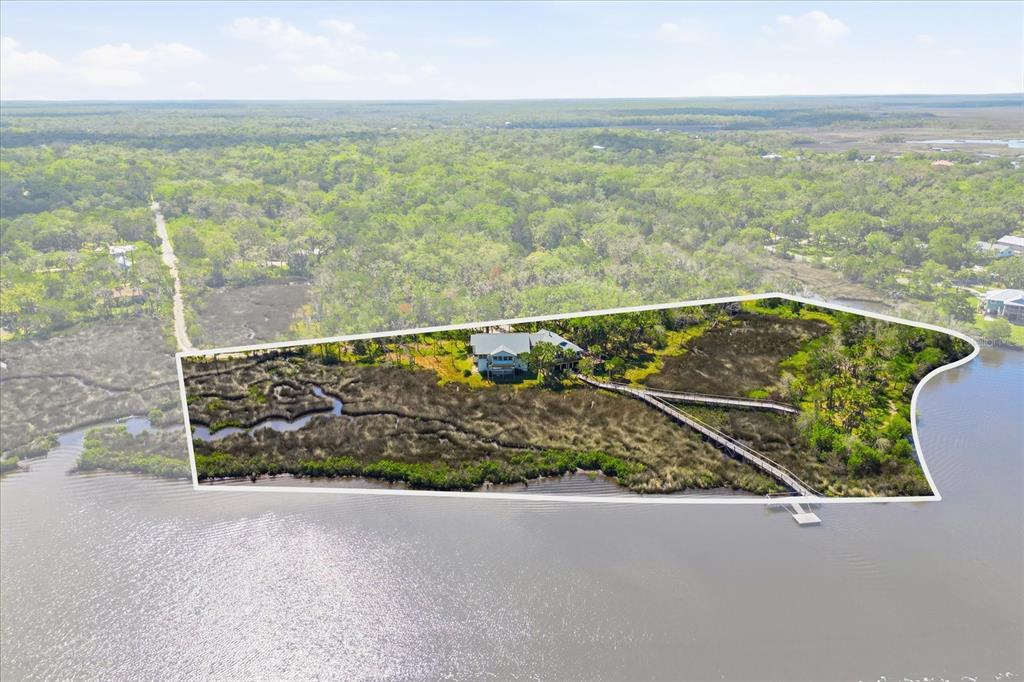 An aerial view shows a house situated on a marshy waterfront lot with a boardwalk — 12350 W RED MAPLE STREET, HOMOSASSA, FL