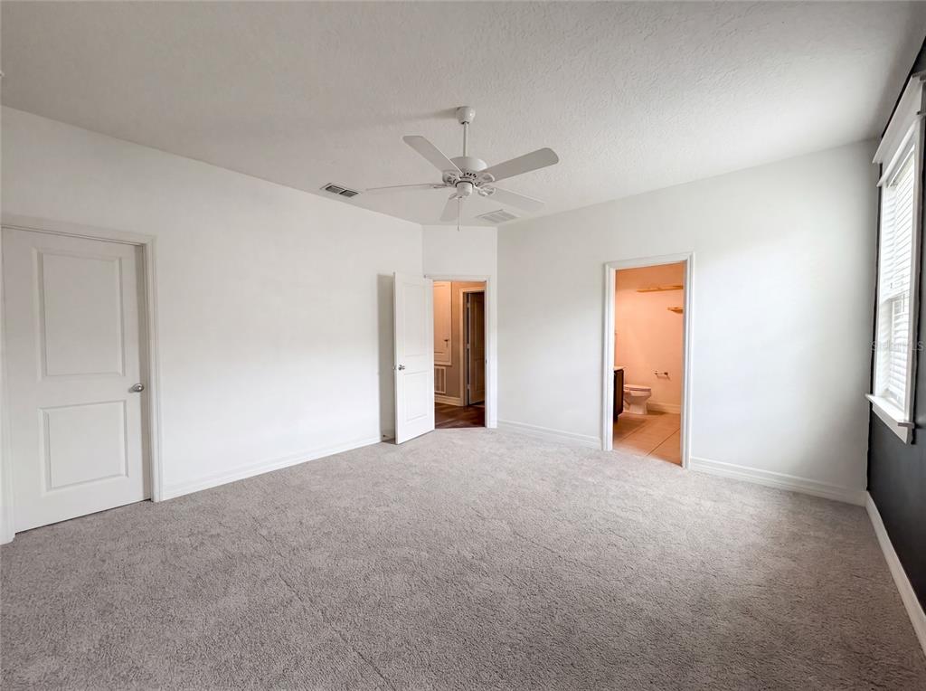 A bedroom with gray carpet, white walls, a ceiling fan, and two doorways — 10029 WEATHERS LOOP, CLERMONT, FL