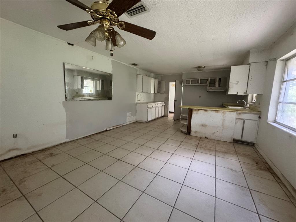 A kitchen with white cabinets, a tile floor, and a ceiling fan in a fixer-upper — 6187 OGBURN STREET, BROOKSVILLE, FL