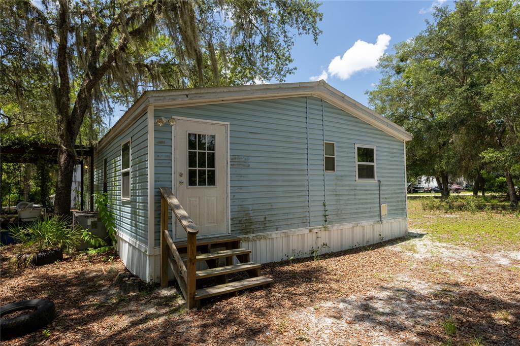 A stacked washer and dryer stand in a narrow hallway leading to a kitchen area — 108 KITTY AVENUE, INTERLACHEN, FL