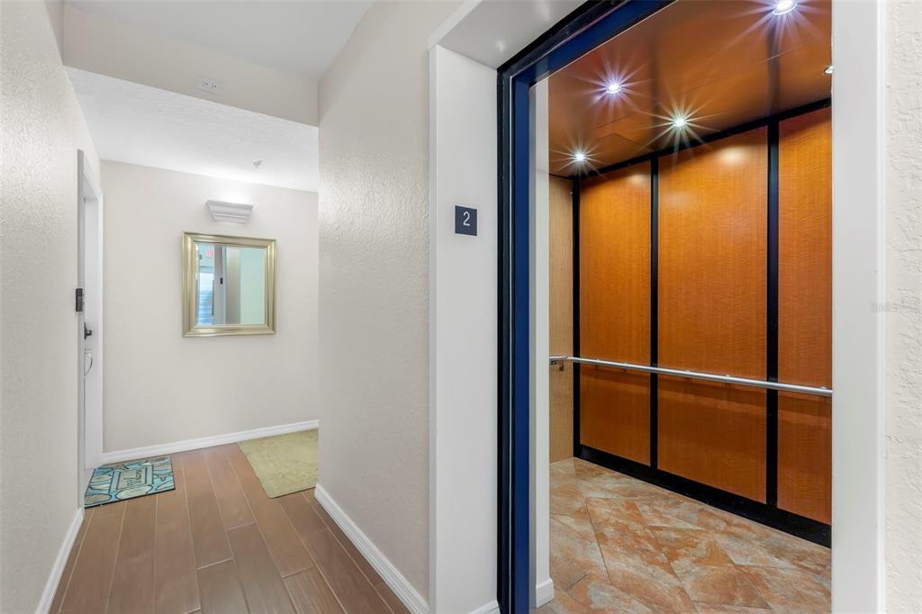A white front door with a decorative glass insert sits beside a large gold-framed mirror — 1695 PINELLAS BAYWAY S UNIT D1, TIERRA VERDE, FL