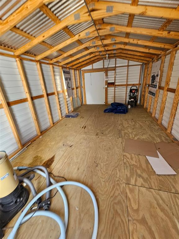 An interior view of a shed featuring wood-paneled flooring, exposed wooden rafters, and metal walls — 14150 E 6TH LANE, WILLISTON, FL