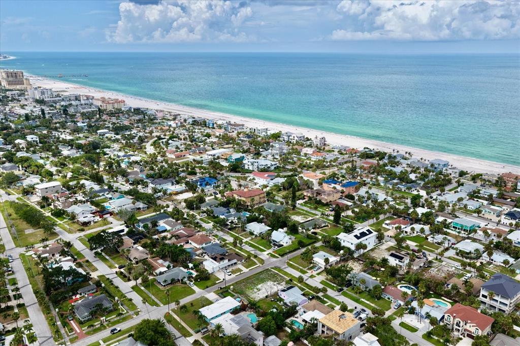 An aerial view shows a coastal neighborhood with houses, palm trees, and a sandy beach — 835 BRUCE AVENUE, CLEARWATER BEACH, FL