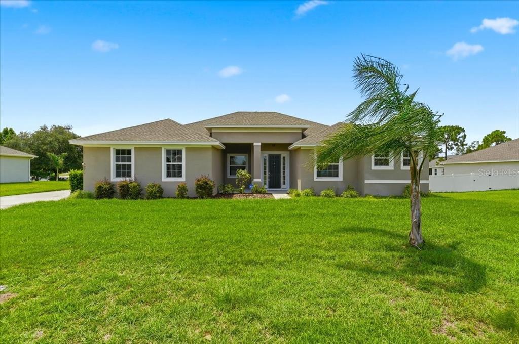 A single-story suburban house with a tan exterior, a palm tree, and a green lawn — 5071 MOSS HAMMOCK TRAIL, SEBRING, FL
