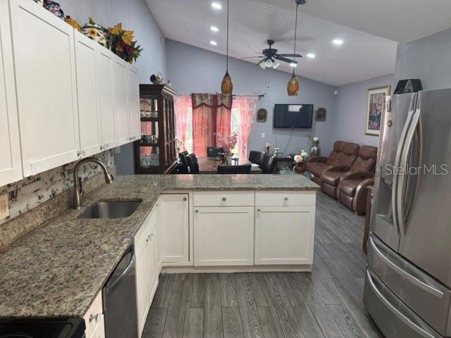 A kitchen with white cabinets and granite countertops opens into a living and dining area — 6567 MERITMOOR CIRCLE, ORLANDO, FL
