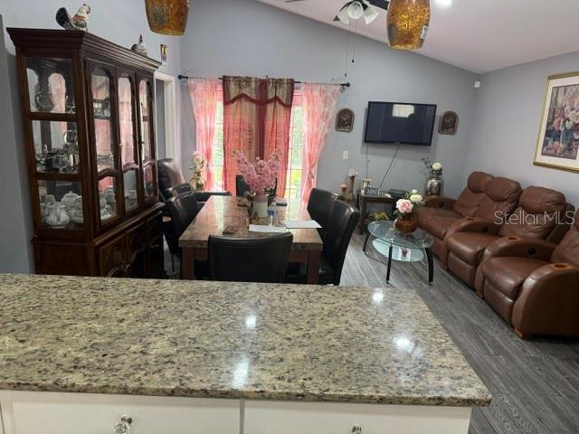 A dining area and living room feature a granite-topped island, wood furniture, and leather recliners — 6567 MERITMOOR CIRCLE, ORLANDO, FL