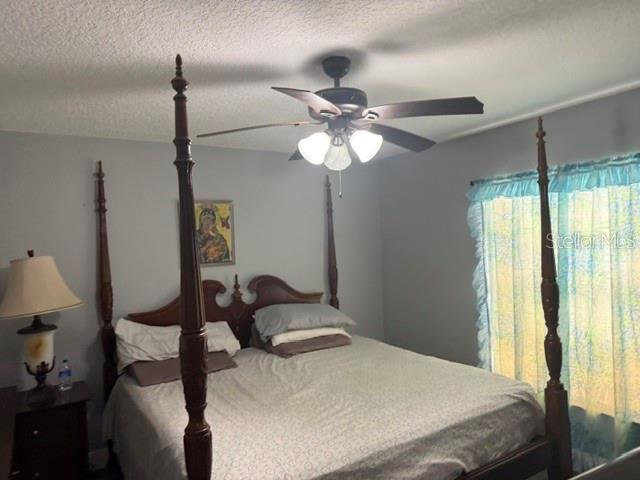 A bedroom features a four-poster wooden bed, a ceiling fan, and a window with curtains — 6567 MERITMOOR CIRCLE, ORLANDO, FL