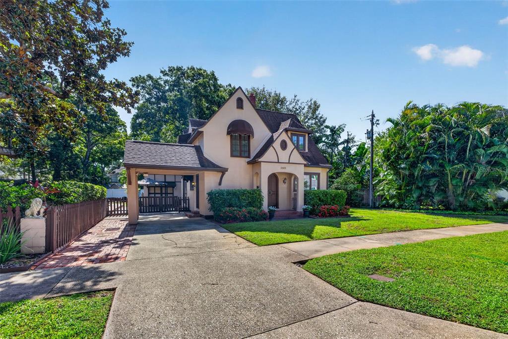 A two-story stucco house with a front-facing gable, a carport, and a manicured lawn — 2321 14TH STREET N, ST PETERSBURG, FL
