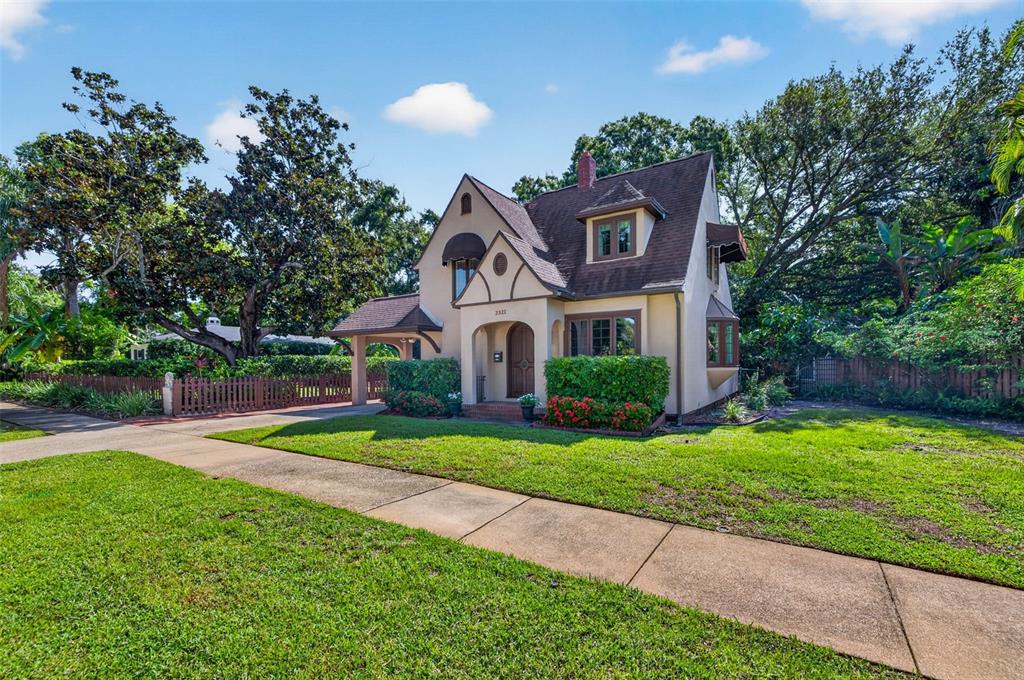 A two-story stucco house with a brown shingled roof, arched entryway, and a side carport — 2321 14TH STREET N, ST PETERSBURG, FL