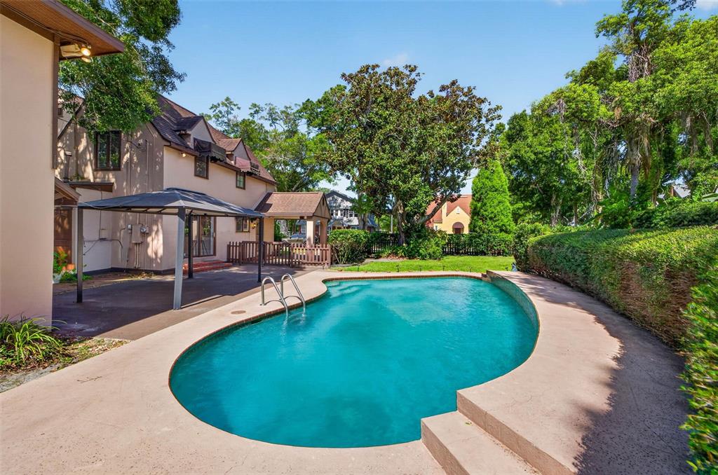 A backyard features a swimming pool with a ladder next to a house and gazebo — 2321 14TH STREET N, ST PETERSBURG, FL