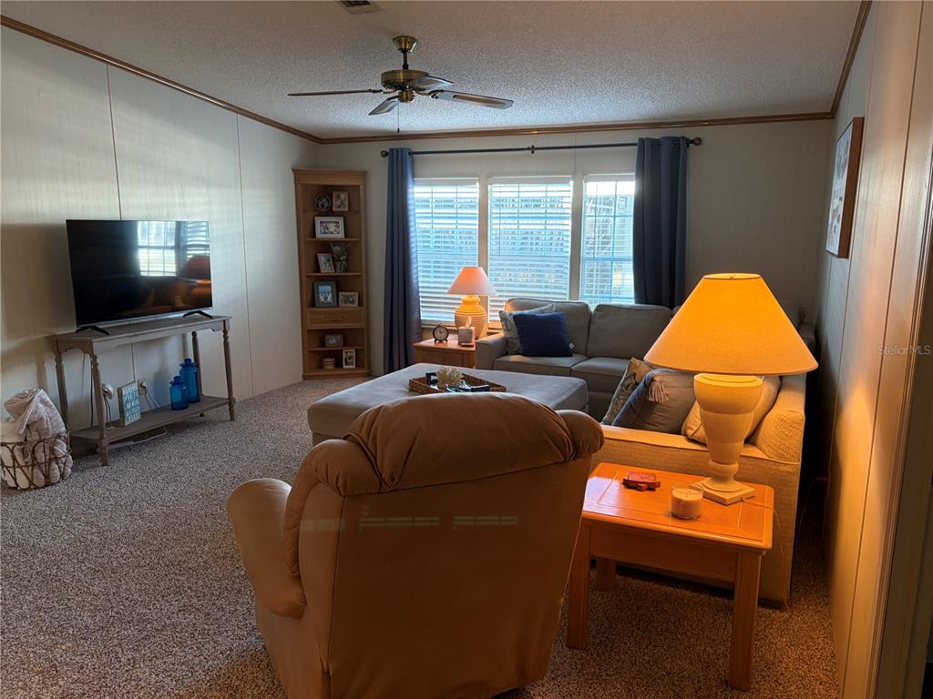 A living room features a beige sofa, a recliner, a television, and a corner bookshelf — 260 RAMSGATE WAY, HAINES CITY, FL