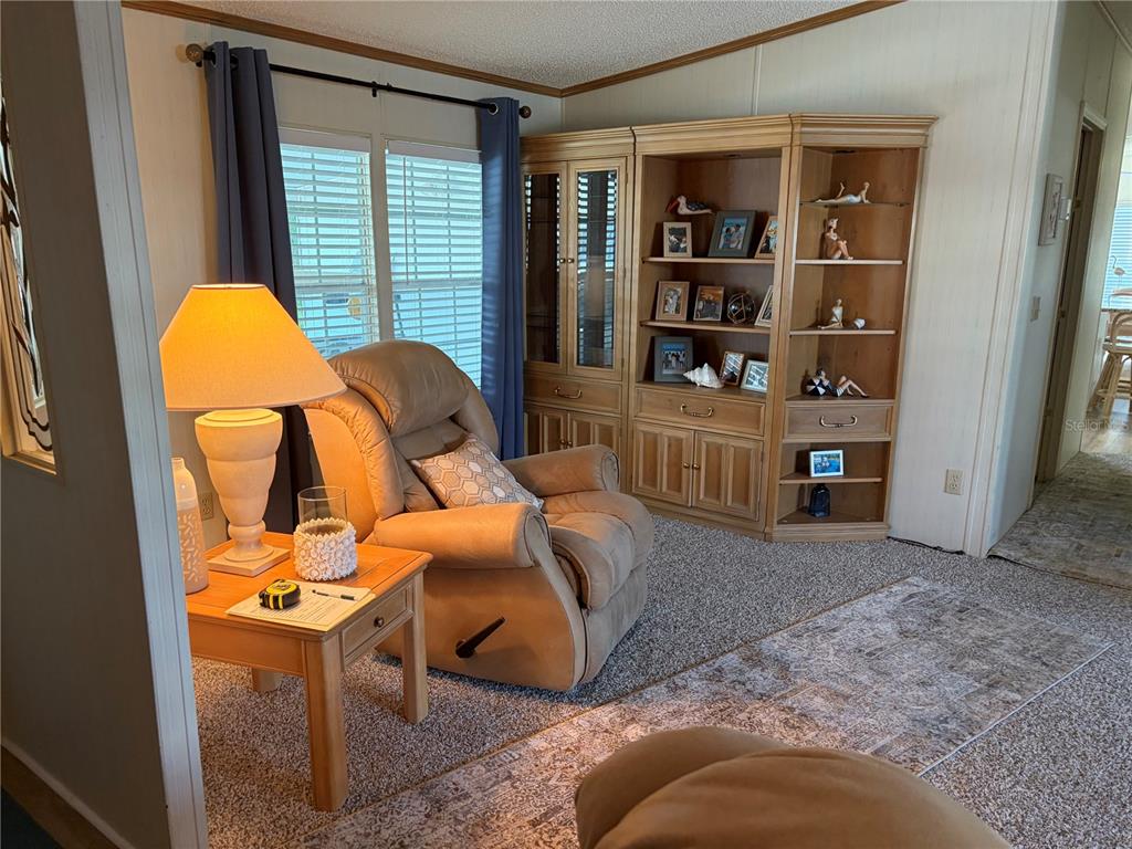A living room features a tan recliner, a wooden side table, and a large corner bookcase — 260 RAMSGATE WAY, HAINES CITY, FL