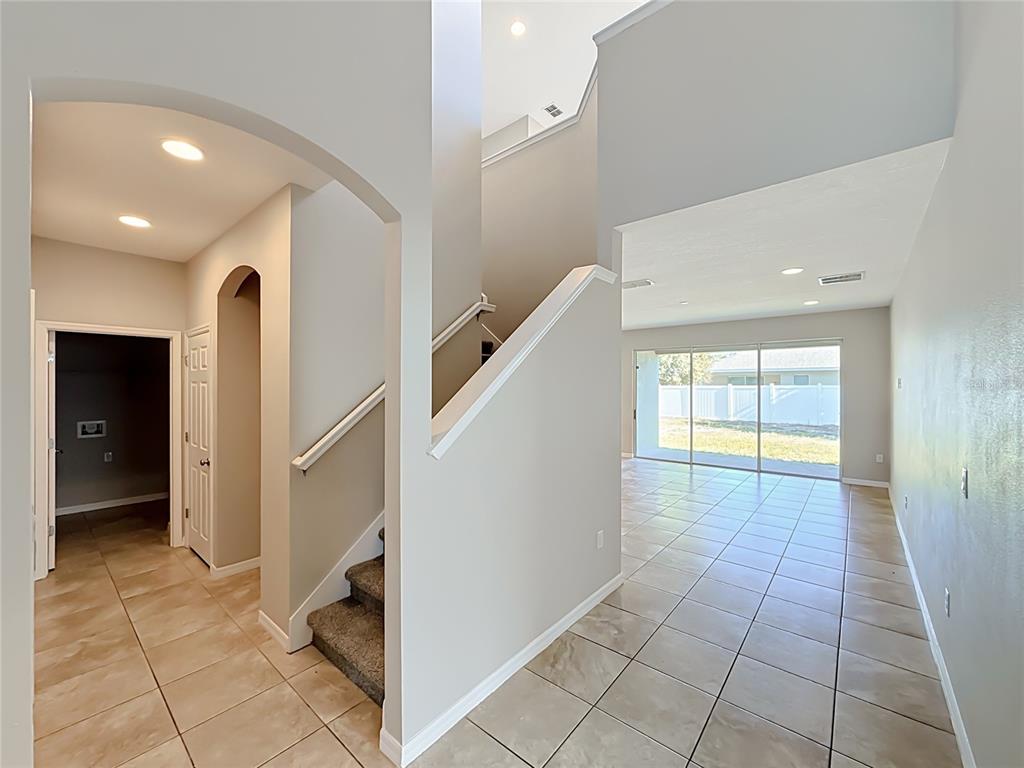 An interior view shows a tiled entryway, a staircase, and a living area with sliding doors — 3319 BETHPAGE LOOP, MOUNT DORA, FL