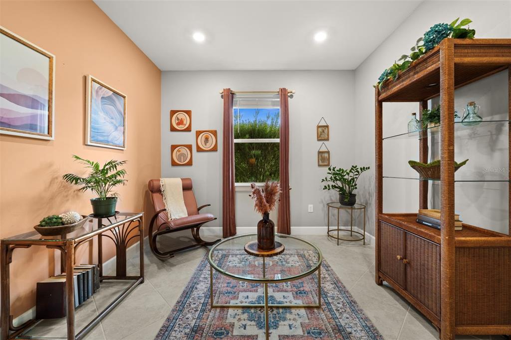 A sitting room features a peach accent wall, a glass coffee table, and rattan furniture — 43047 PARKSIDE COURT, PUNTA GORDA, FL