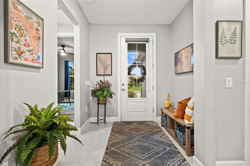 A bright entryway features a white front door, a patterned rug, and a wooden bench — 43047 PARKSIDE COURT, PUNTA GORDA, FL