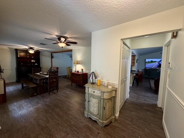 A living room features leather sofas, a ceiling fan, and a long wall-mounted display shelf — 155 WOODCUTTER LANE, PALM HARBOR, FL