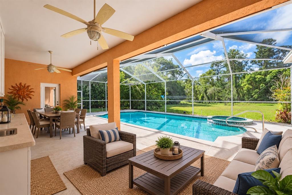 A screened-in patio features a swimming pool, a raised hot tub, and a covered area — 13566 RUDI LOOP, SPRING HILL, FL