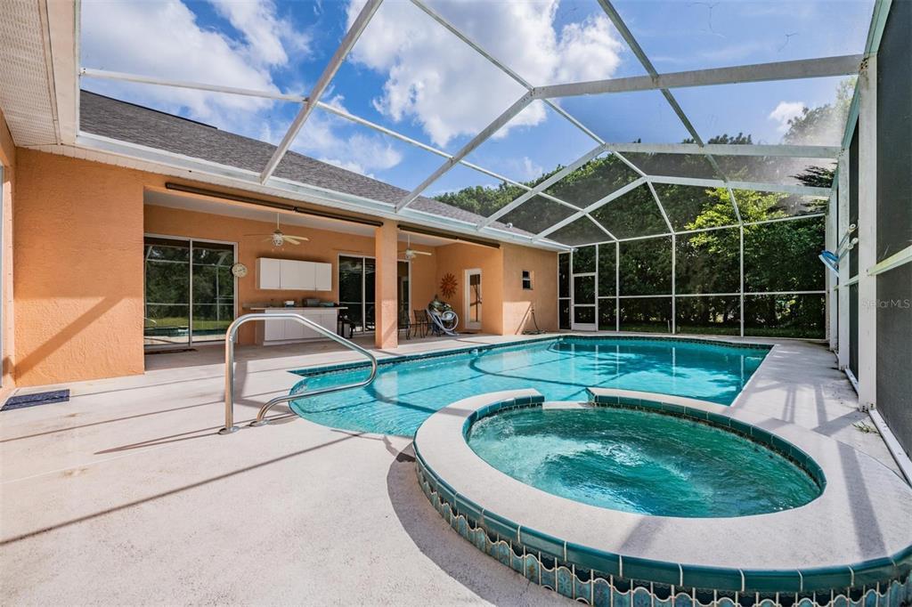 A single-story house with a two-car garage and a concrete driveway at sunset — 13566 RUDI LOOP, SPRING HILL, FL