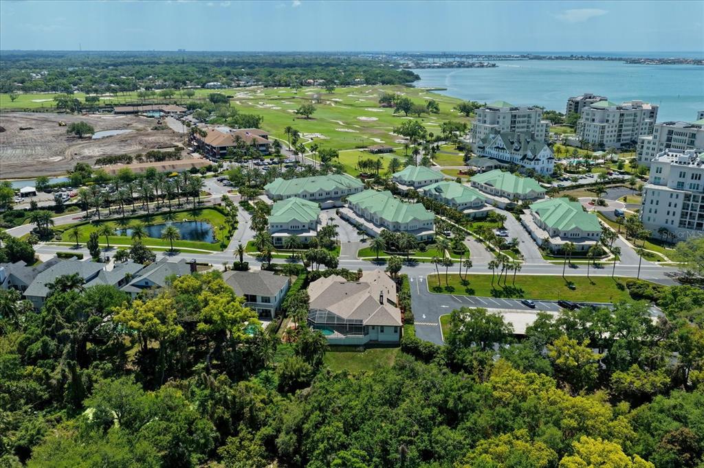 An aerial view shows a residential neighborhood with green-roofed buildings, a golf course, and water — 280 BELLEVIEW BOULEVARD, BELLEAIR, FL