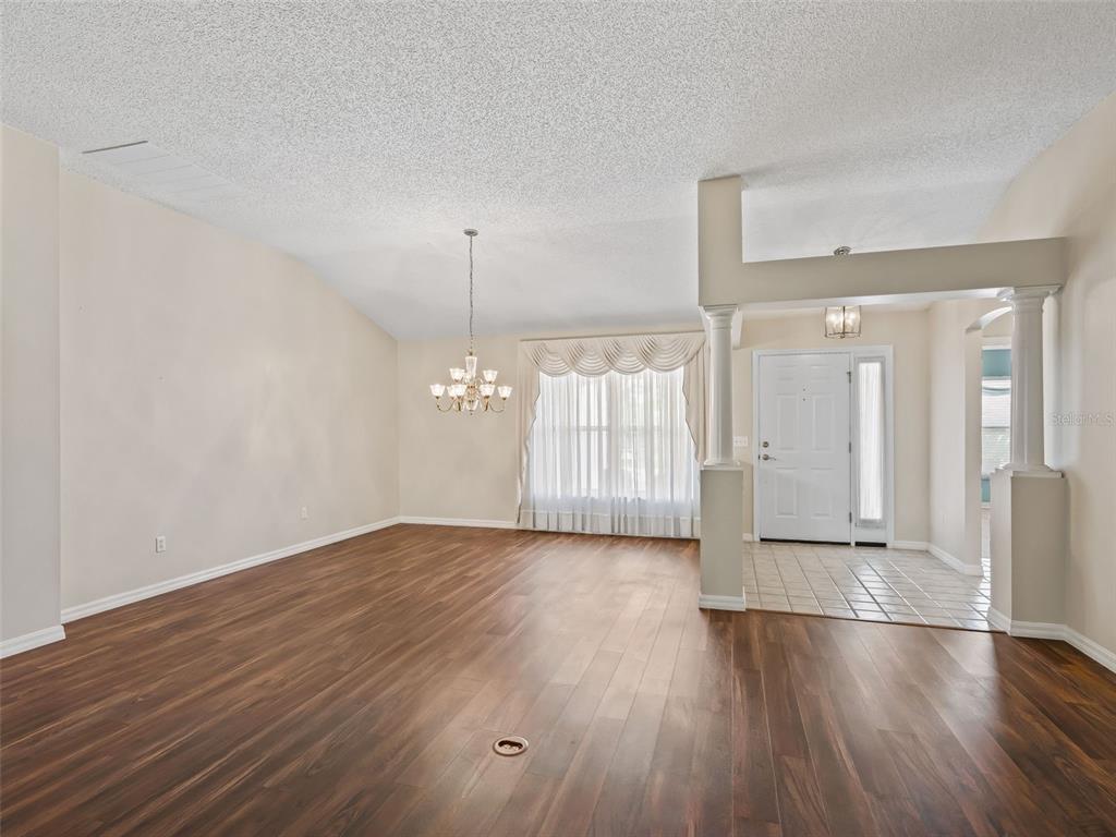 A living room with wood-look flooring, a chandelier, and a tiled entryway with columns — 823 SAN SALVADOR DRIVE, THE VILLAGES, FL